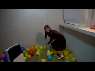 lovely korean girl has lots of fun popping a room full of balloons with a knife